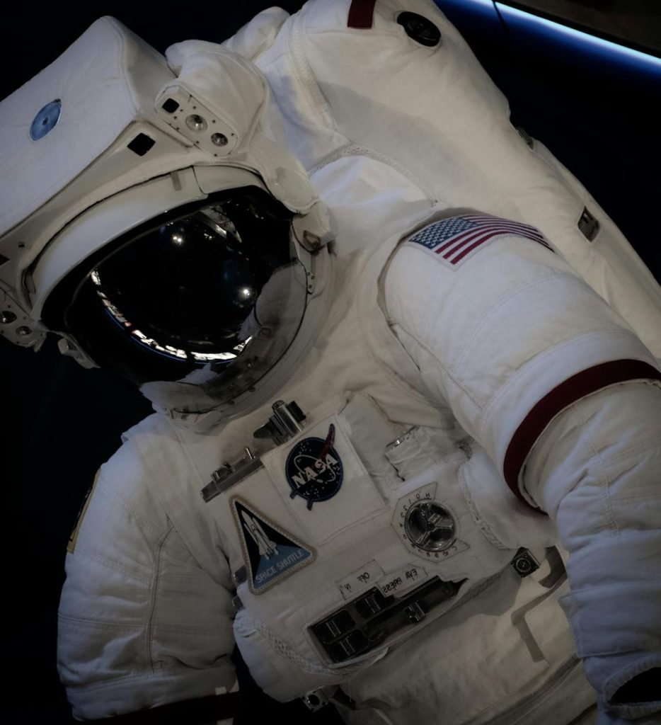 12 Grand Ideas to Supercharge Your Science and Technology News Outputs in Publication, Press Competitions 7 Close-up of an astronaut in a NASA space suit with the US flag, outdoors at Kennedy Space Center.