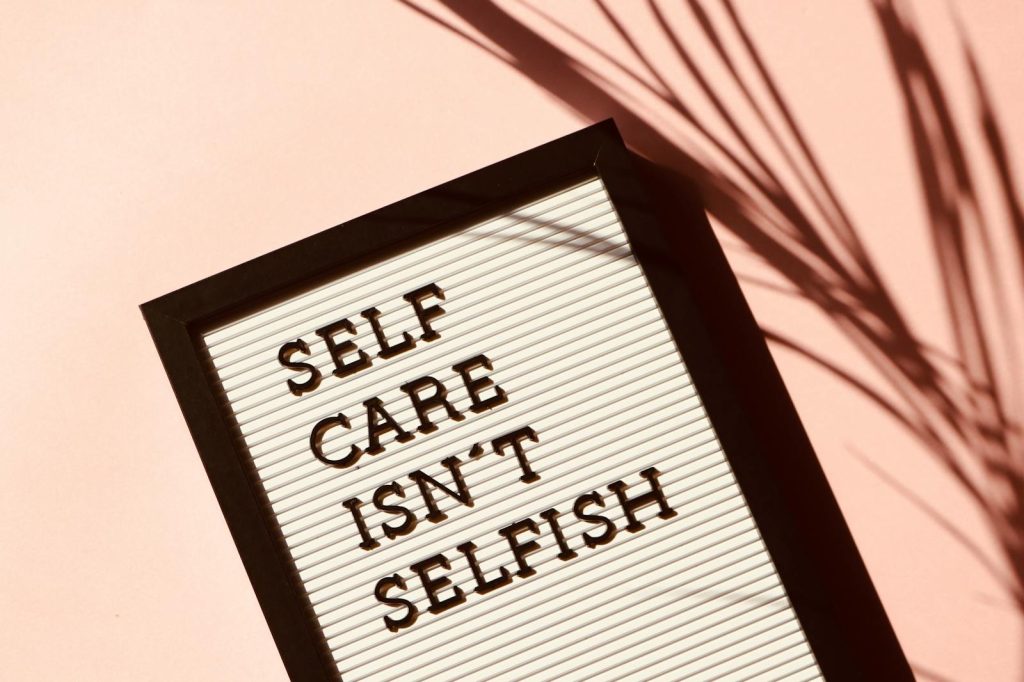 How to Find the Perfect Niche for Your Online Platforms or Social Media Pages in 7 Seconds 6 Letter board displaying 'Self Care Isn't Selfish' with artistic shadow on pink background.