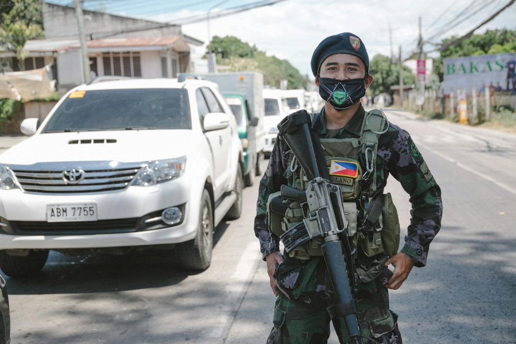 Young Sampaguita Vendor Confronted by Mall Security, Rosmar Tan Reaches Out to Help 7 A Philippine soldier in uniform and mask standing on a city street, showcasing military presence.
