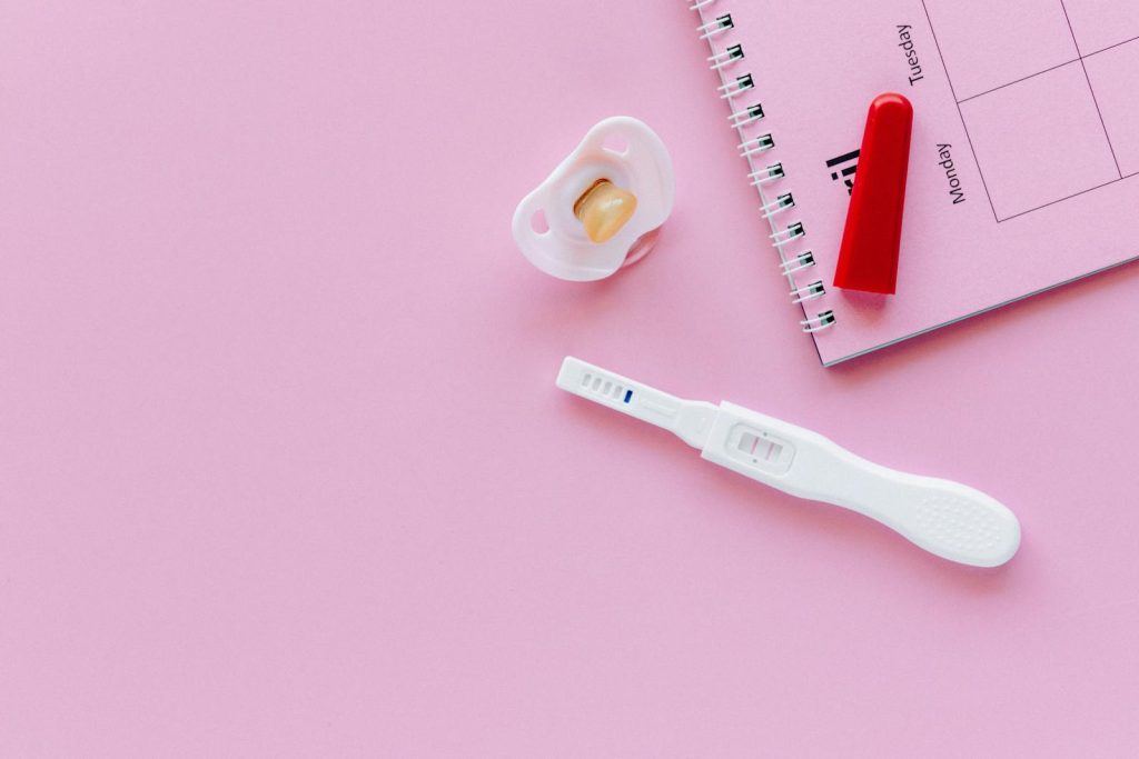 Rise of Teenage Pregnancy is Alarming, DepEd Commits to Health, Well-being of Youth 6 A positive pregnancy test on a pink surface with a pacifier and planner.