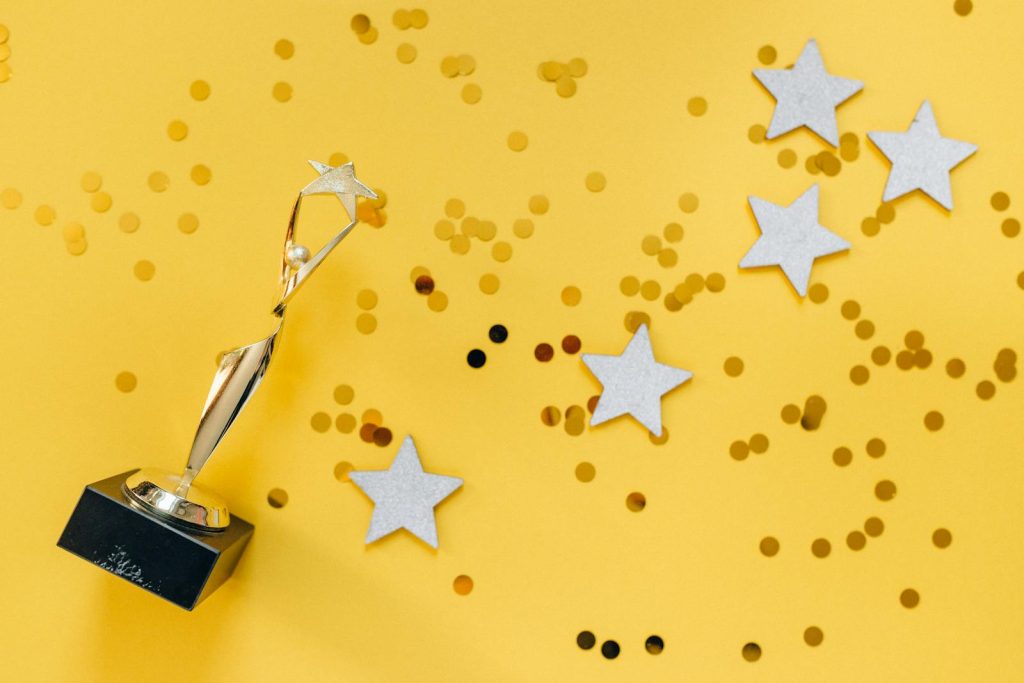 UP Magna Cum Laude Got Rejected in Job Applications Because of Her Accent, and Her Message to Those Having Similar Experiences 6 Shiny golden trophy and stars on a vibrant yellow background, symbolizing success and victory.