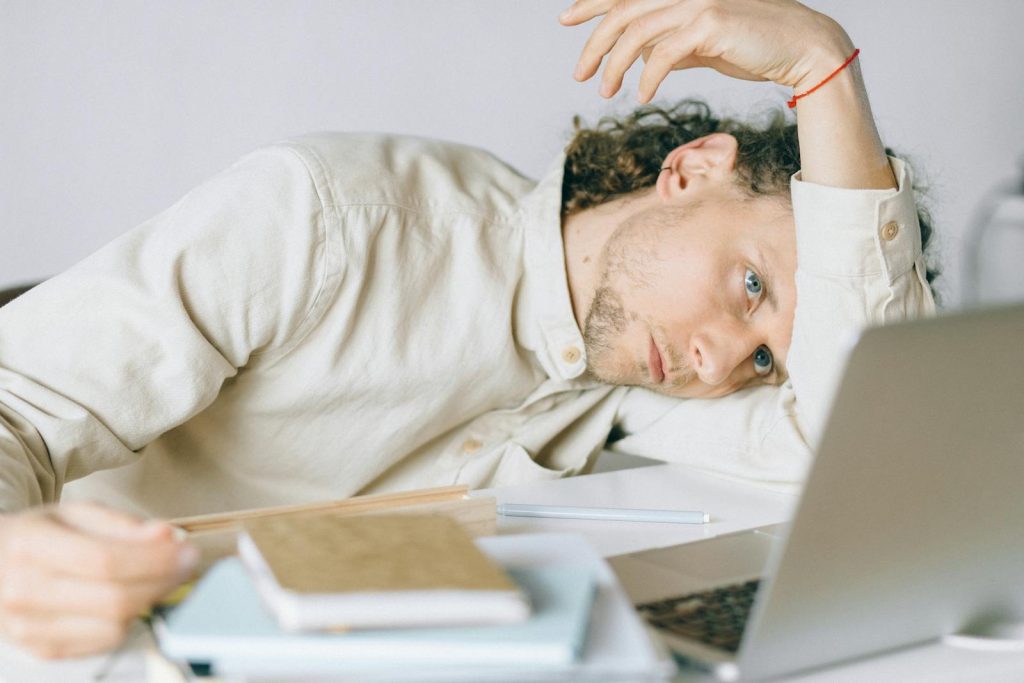 This Problem Degrades Education Quality, Here's 6 Strategies and Solutions to Quash Burnout 6 A tired Caucasian man at a desk, showing signs of exhaustion and stress, exemplifying workplace burnout.