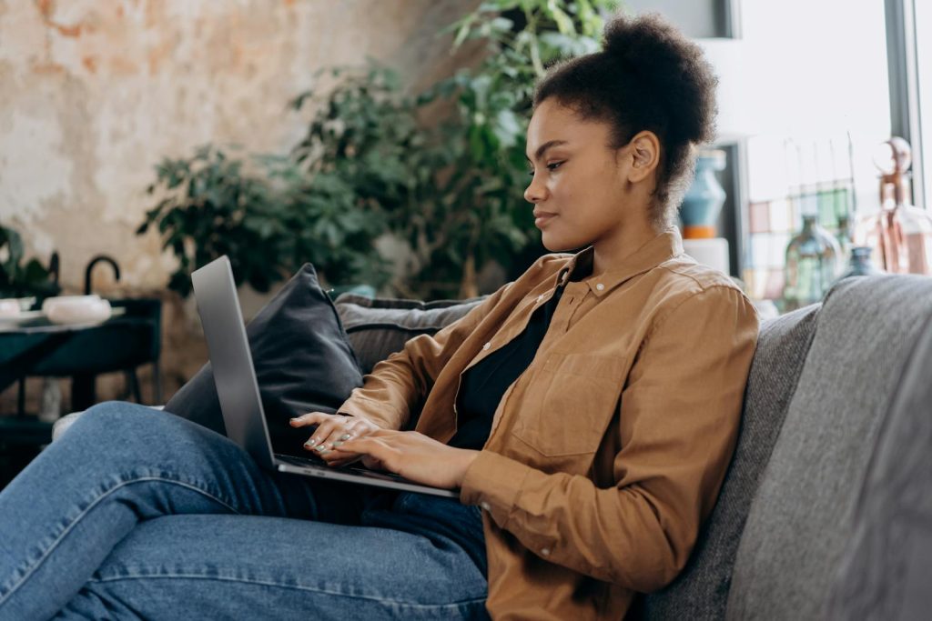 The Only 8 Things You Need to Remember When Conducting Online Interviews 8 A young woman in casual clothing works on her laptop in a cozy home office setting.