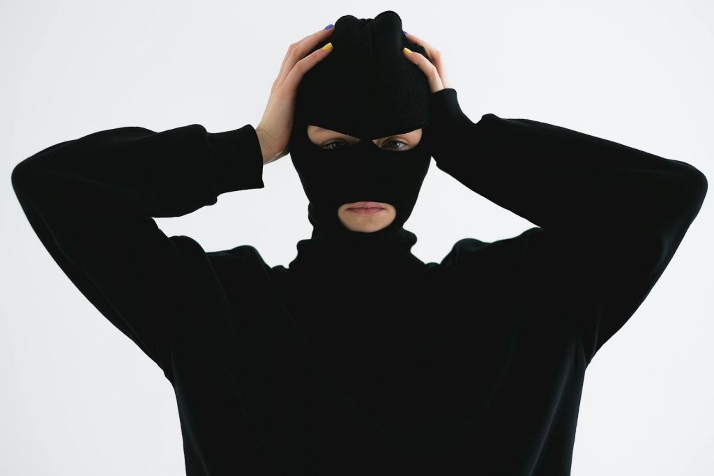 Just Want to Save Money but Student Fell Victim to Riding-in-tandem, and the Lesson He Shared on Social Media 7 A person in a black balaclava with hands on head creates a mysterious and suspenseful vibe.