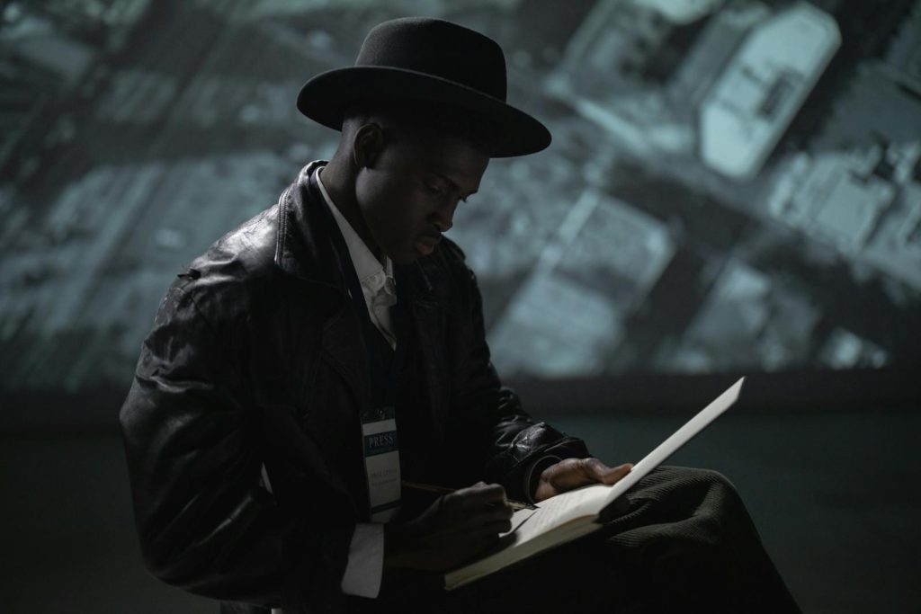 What's the Difference Between Campus Journalism and Actual Journalism in Newspaper Companies? 8 A man in a fedora and leather jacket writes indoors, symbolizing mystery and journalism.