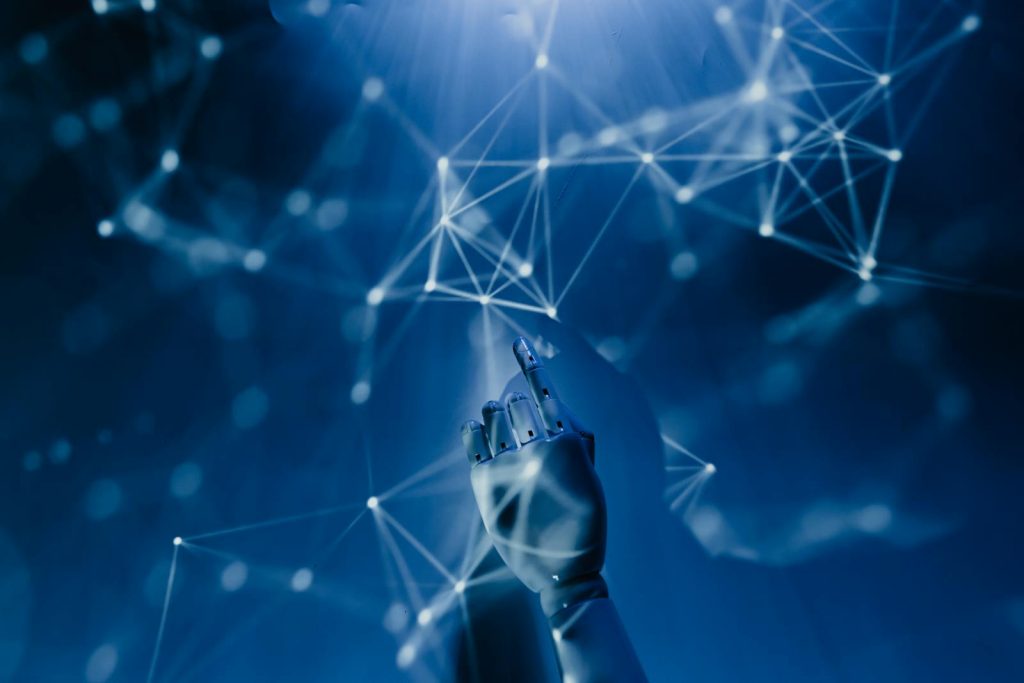 This is How Artificial Intelligence Can Transform Education Glamorously 6 A robotic hand reaching into a digital network on a blue background, symbolizing AI technology.
