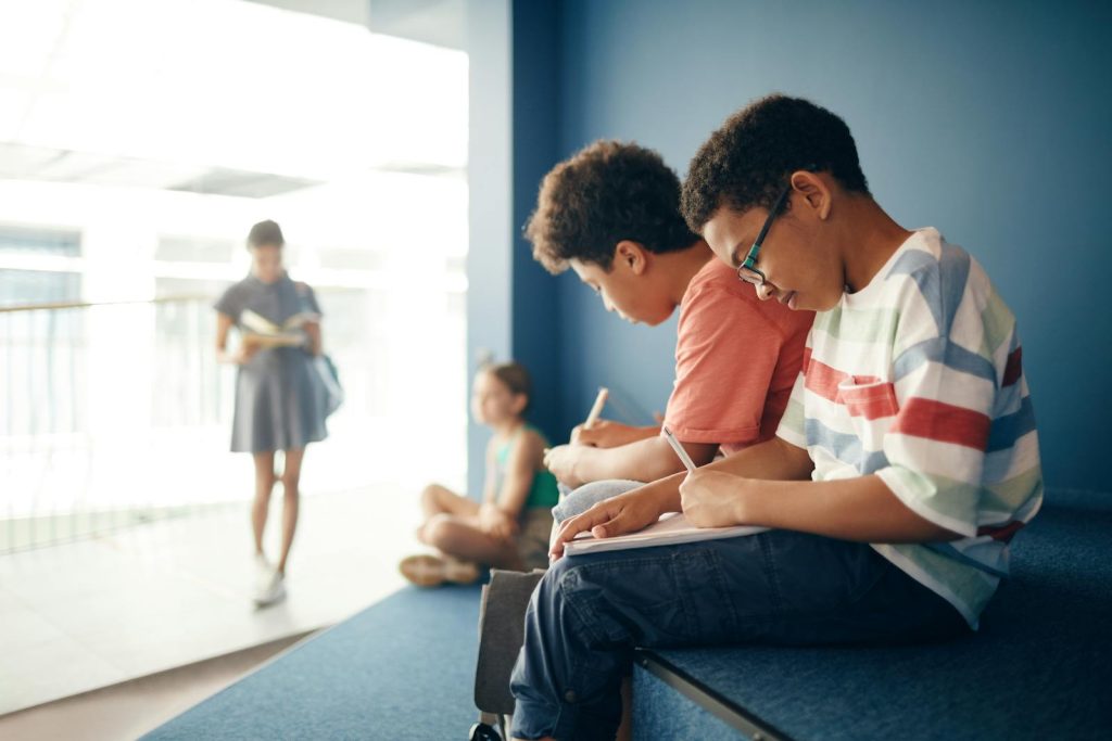 Problem with Classroom Management for Junior High School? Here's How to 10 Techniques to Fix It 8 Diverse group of kids in a school hallway studying and writing notes.
