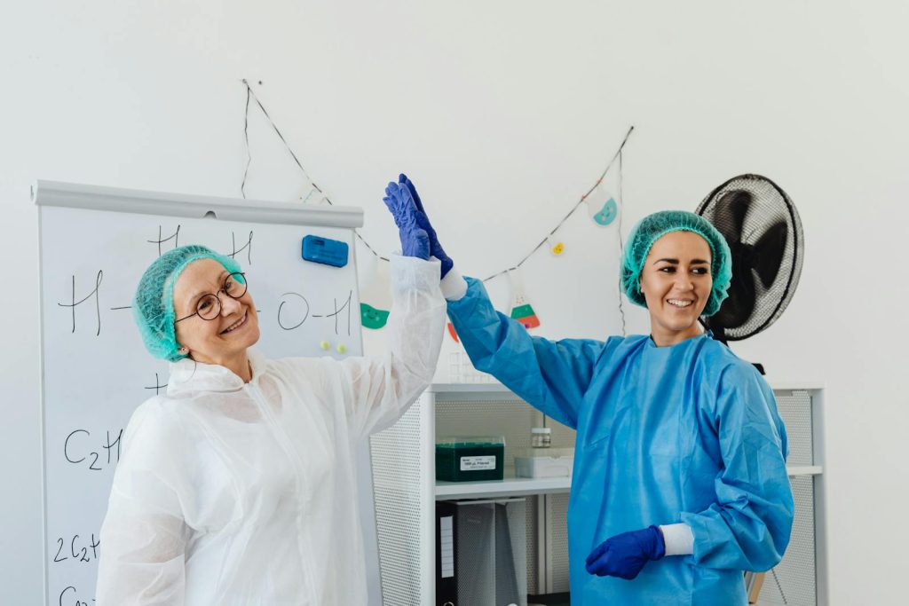 How to Get Rid of Early Pregnancies, Sexually Transmitted Diseases, Gender Neutrality? 9 Two healthcare professionals in PPE high-fiving in a lab, exuding positivity.