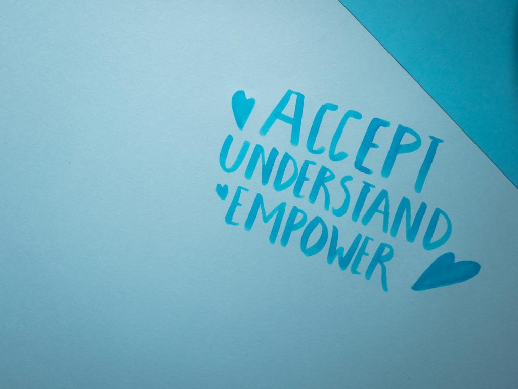 Blue background featuring handwritten words promoting acceptance, understanding, and empowerment.