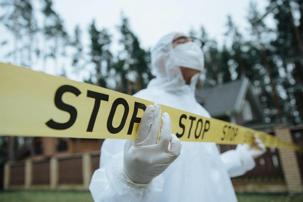 This Woman Spectacularly Sneaks Fifth Place in Criminologists Exam 5 Investigator in protective gear securing crime scene with stop tape outdoors.