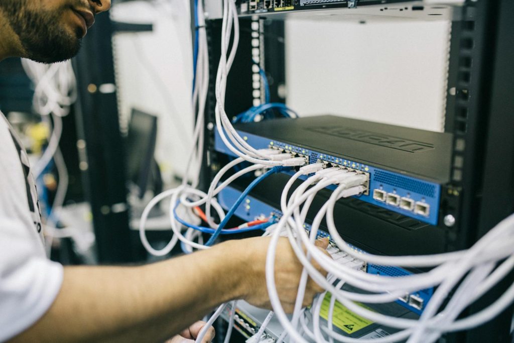 Stayed Up Late Playing Games but Became Topnotcher in 2 Board Exams - He Credits Importance of Effective Study Techniques 6 An IT professional configuring network cables in a server rack, focusing on Ethernet connections.