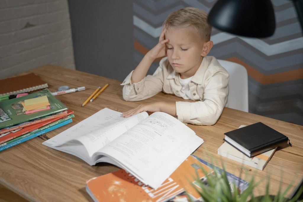 7 Popular Strategies to Encourage Active Engagement from Grade School Pupils 5 A young boy appears deep in thought while studying at his desk filled with books and notebooks.