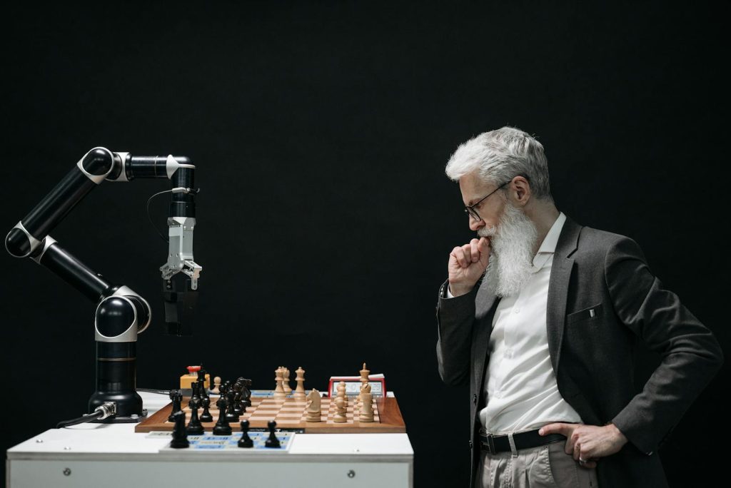 Can PH Keep Pace? The Concerning Rise of AI and Issue of Possible Massive Job Layoffs 5 An elderly scientist contemplates a chess move against a robotic arm on a chessboard.