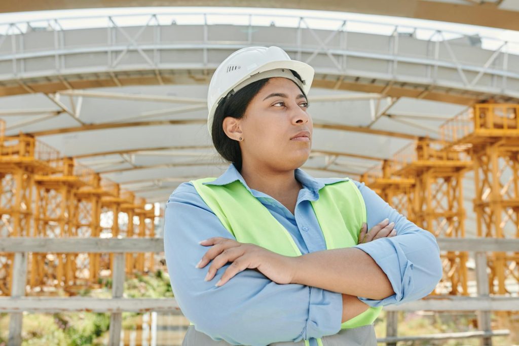 Top 10 Insanely High-Paying Careers in the Philippines - For Your Career Guidance 7 Young female engineer crossing her arms at a construction site, wearing a hardhat and reflective vest.