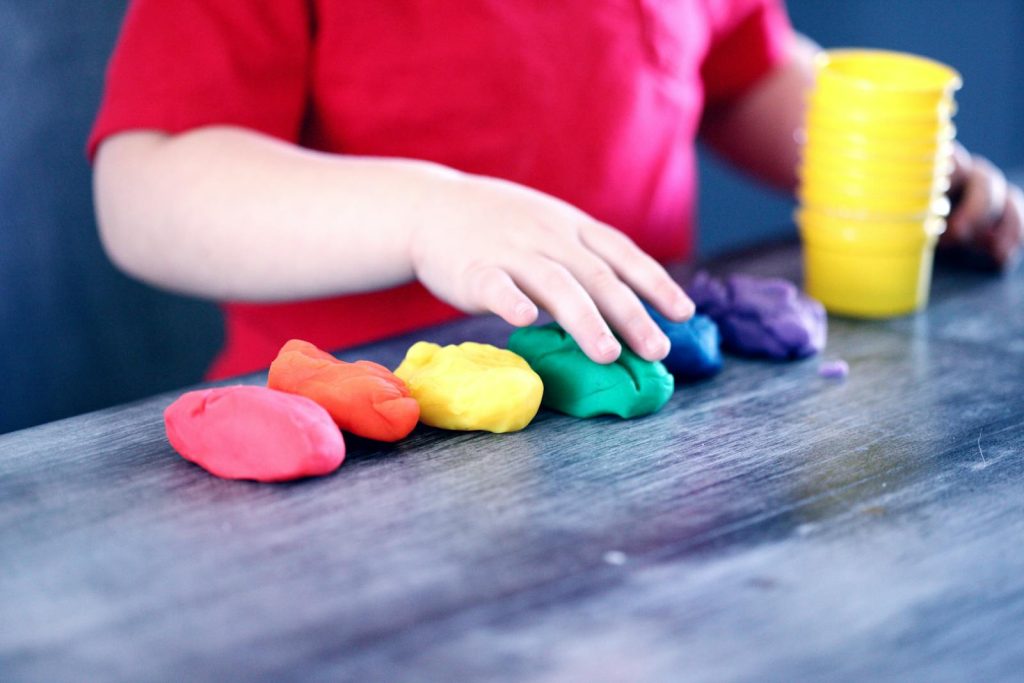 How to Create a Safe Philippines for Children? Series of Activities for Child Safety This 32nd Children's Month Launched 7 A young child with rainbow-colored modeling clay and stacking cups on a table indoors.