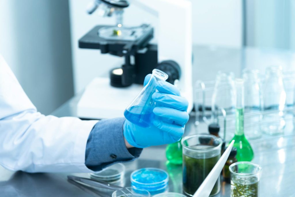 10 Tips to Dominate Your Next ScieTech Writing Contest and Triumph in NSPC 5 Scientist in gloves analyzing blue liquid in a laboratory setting with microscope and glassware.