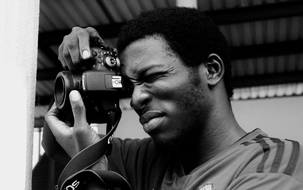 10 Must-Remember Tips to be Better at Photojournalism 5 Monochrome portrait of a man skillfully using a camera, capturing a moment.
