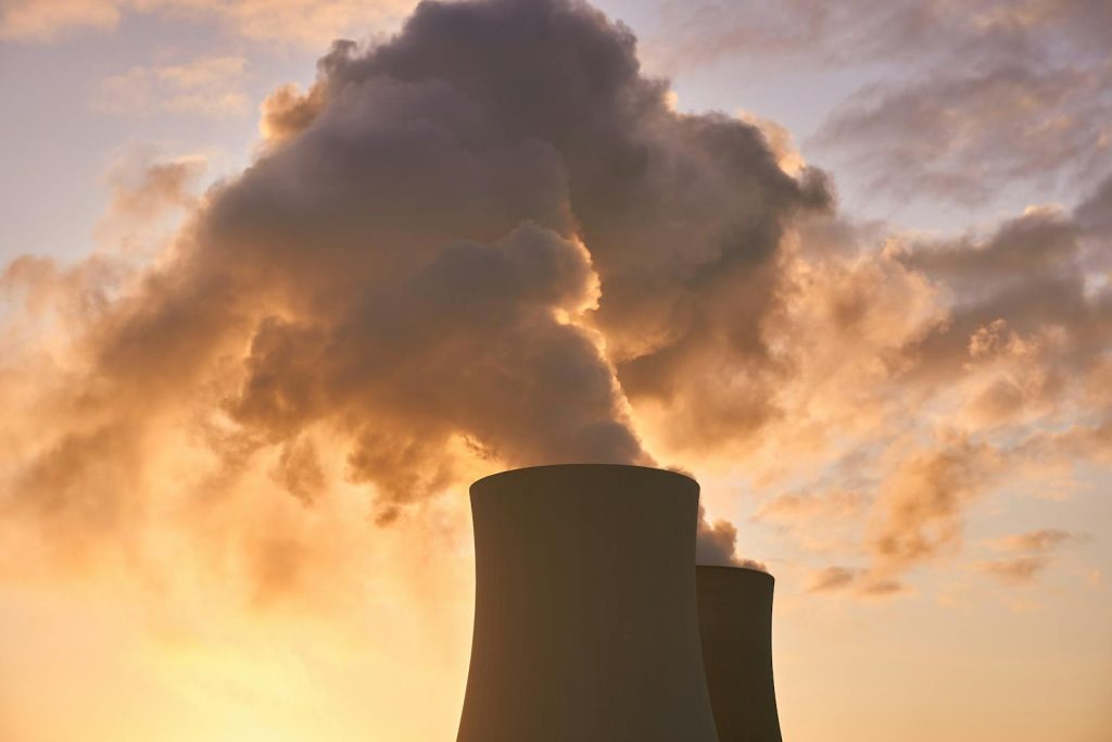 Air Quality in Philippines is Deteriorating. Here Are Suggested Attitude to Mitigate the Problem 5 Cooling towers release smoke into a dramatic sunset sky, highlighting environmental impact.