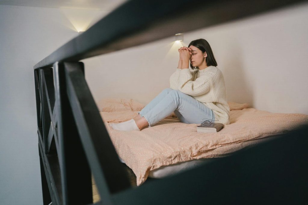 10 Tips to Dominate Your Next ScieTech Writing Contest and Triumph in NSPC 9 Woman in a cozy knitted sweater meditates peacefully on the bed with closed eyes and praying hands.