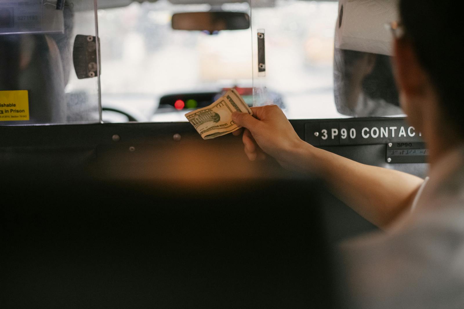 Jeep Driver Refused His Fare, Reminisces How He Helped When Driver Was in Need of Food 6 Closeup of a person handing cash to a taxi driver through the partition during a ride in a busy city.