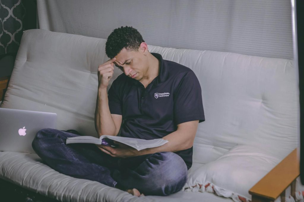 Is It About Acquiring Medals? No. Here is the Real Purpose of Education and the Critical Stage You Don't Want to Miss 6 A student relaxing on a sofa, studying with a book and using a laptop indoors.