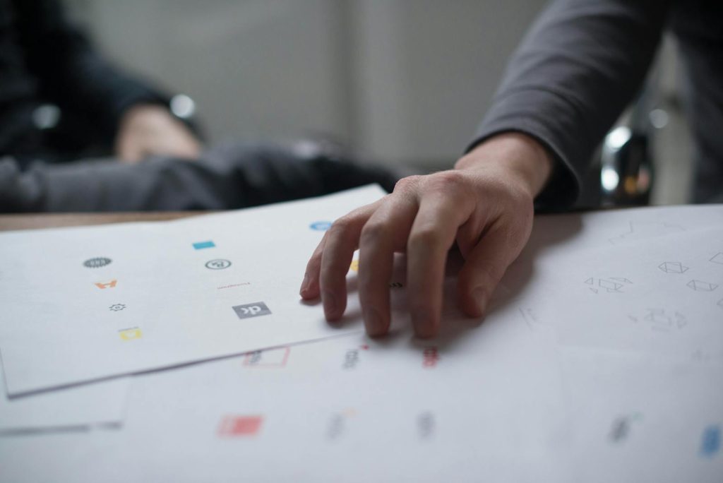 Interleaved Practice Makes You Learn Several Skills at Once 5 A close-up shot of a hand reviewing various logo designs on paper, ideal for business concepts.