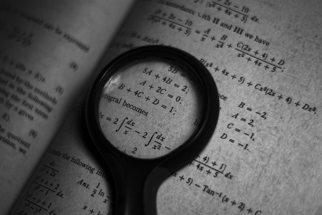Math is Very Important in Everyday Life but the World Struggles with It 8 A magnifying glass focuses on mathematics formulas in a book, enhancing study and exploration.