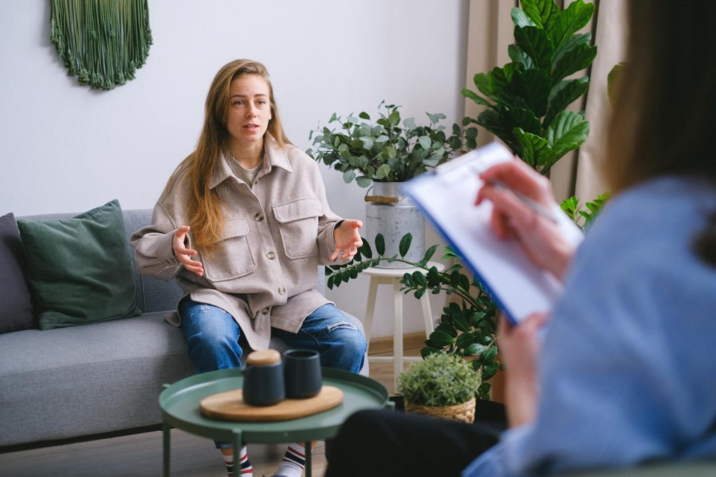 4 Easy Steps to Utilize Self-Explanation, Effective Strategy to Make Sense of New Information & Deeper Understanding 6 A woman engages in a therapy session, discussing issues with a counselor inside a modern office.
