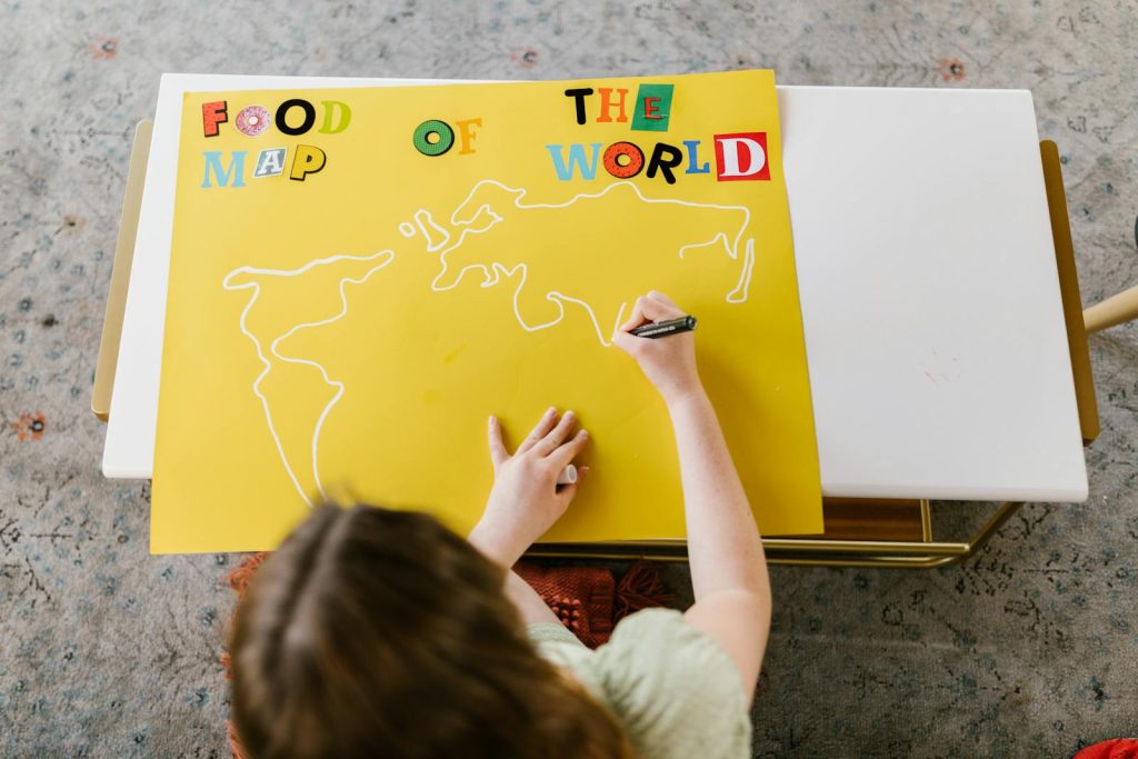 7 Tips on How to Use Dual Coding - The Powerful Combo of Words and Visuals to Double Your Learning Efficiency 5 A child draws on a yellow Food Map of the World poster, showcasing creativity and education.