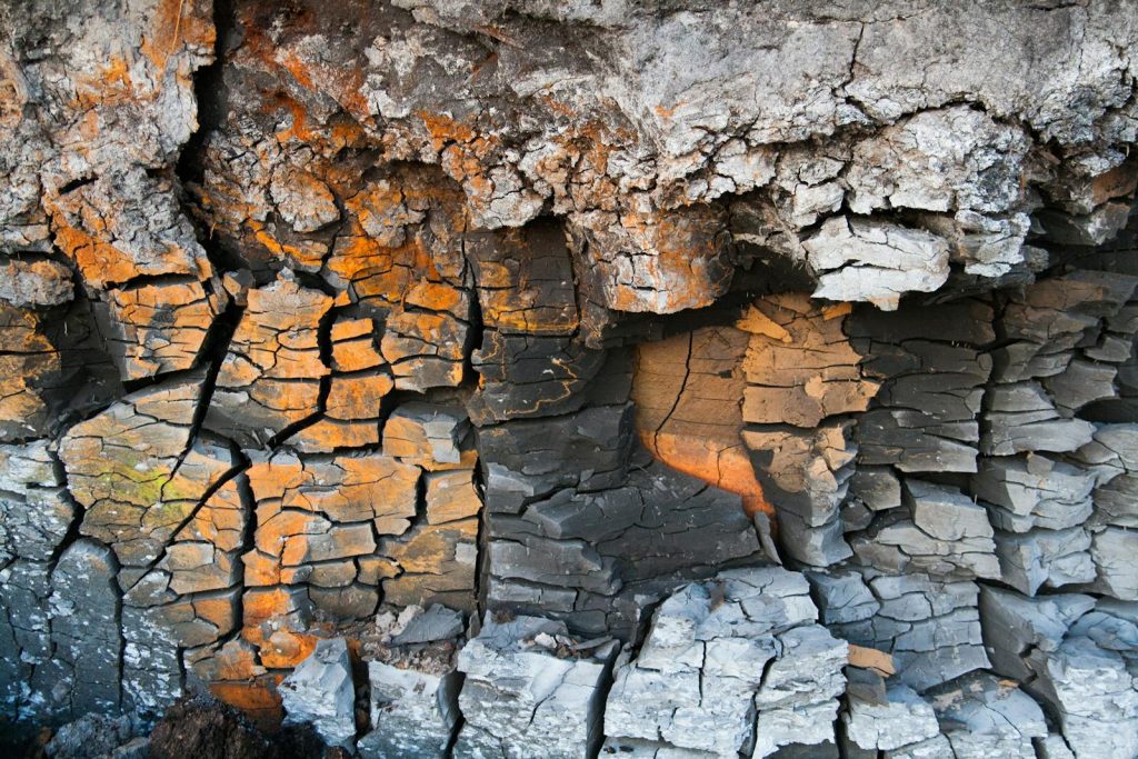 Detailed close-up of cracked earth texture in Ventspils, Latvia, with orange and grey patterns.